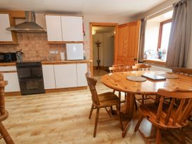 A kitchen with wooden table and chairs white cabinets and a stove at Henblas Cottage in Rhyd-Y-Foel