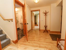 A hallway with wooden flooring a coat stand and an open door leading to a bathroom at Henblas Cottage in Rhyd-Y-Foel
