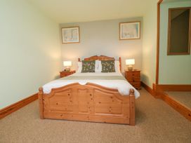 A bedroom with a wooden double bed two bedside tables with lamps and framed pictures on the wall at Henblas Cottage in Rhyd-Y-Foel