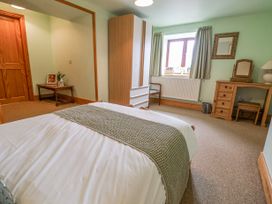 A bedroom with a bed a wardrobe a dressing table and a chair at Henblas Cottage in Rhyd-Y-Foel