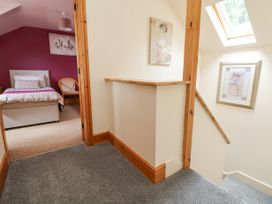 A hallway with stairs and two framed pictures next to a bedroom with a bed and chair at Henblas Cottage in Rhyd-Y-Foel