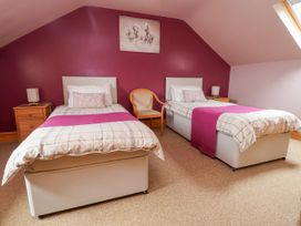 A bedroom with two single beds side by side with nightstands and lamps and a chair in between at Henblas Cottage in Rhyd-Y-Foel