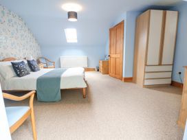 A bedroom with a bed two chairs a wardrobe a chest of drawers and a skylight at Henblas Cottage in Rhyd-Y-Foel