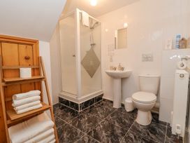 A bathroom with a shower cubicle sink toilet wooden shelves with towels at Henblas Cottage in Rhyd-Y-Foel