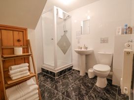 A bathroom with a shower enclosure sink toilet and towels on a wooden rack at Henblas Cottage in Rhyd-Y-Foel