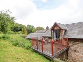 A stone house with a small balcony and metal railing overlooking a grassy area at Henblas Cottage in Rhyd-Y-Foel