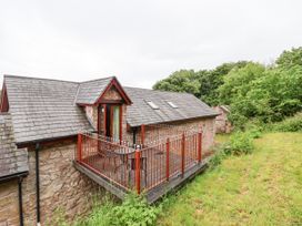 A stone cottage with a rooftop balcony and red railings surrounded by greenery at Henblas Cottage in Rhyd-Y-Foel