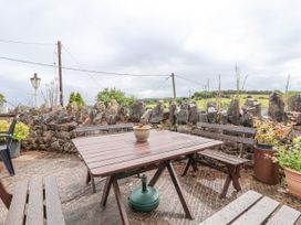 An outdoor patio with wooden benches and table surrounded by stone wall and plants at Henblas Cottage in Rhyd-Y-Foel