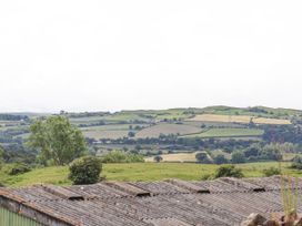 A rural landscape with green fields trees and hills viewed over a corrugated metal roof at Henblas Cottage in Rhyd-Y-Foel