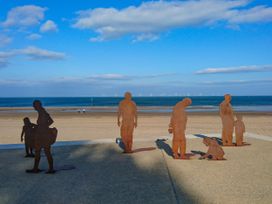 Metal silhouettes of people on a beach with sea and wind turbines in the background at Henblas Cottage in Rhyd-Y-Foel