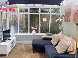 A conservatory with a sofa and television at Apple Tree Cottage Upton near Ringstead Bay