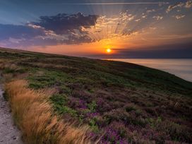 A sunset over hills and ocean at 11 Manleigh Park in Combe Martin