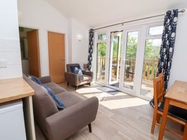 A living room with sofa armchair wooden dining table and glass doors opening to a balcony at Chalet Log Cabin C9 in Combe Martin