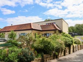 A building with a tiled roof surrounded by bushes and flowers at Chalet Log Cabin C9 in Combe Martin