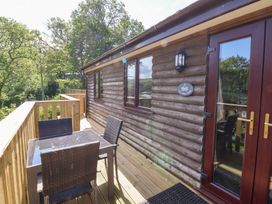 A wooden deck with a table and four chairs outside a log cabin at Chalet Log Cabin L3 in Combe Martin