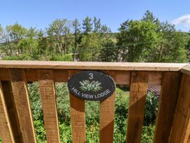 A wooden balcony railing with a sign reading 3 Hill View Lodge with trees and hills in the background at Chalet Log Cabin L3 in Combe Martin