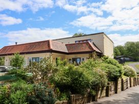 A house with tiled roof surrounded by greenery and a pathway leading to another building at Chalet Log Cabin L3 in Combe Martin