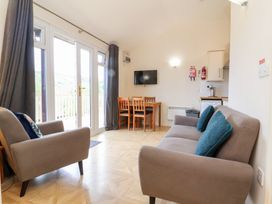 A living room with two sofas a wooden dining table with chairs and a wall mounted TV at Chalet Log Cabin L10 in Combe Martin
