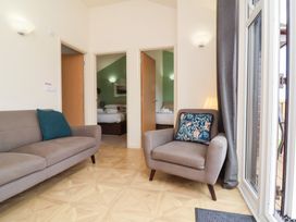 A sitting area with a sofa and armchair facing two open doors showing bedrooms at Chalet Log Cabin L10 in Combe Martin
