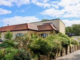 A building with a red tiled roof and garden in front surrounded by wooden fencing at Chalet Log Cabin L10 in Combe Martin