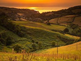 A scenic view of fields and hills at sunset near the coast at 10 Manleigh Park Combe Martin