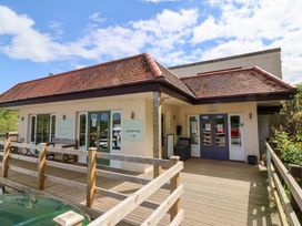 Exterior view of a building with a wooden deck and railings and doors labeled reception and check in at Chalet Log Cabin L12 in Combe Martin