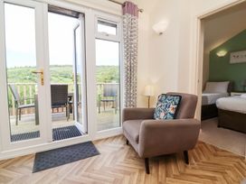 A living area with an armchair and glass doors opening to a balcony with chairs at Chalet Log Cabin L14 in Combe Martin