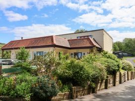A building with a red-tiled roof surrounded by greenery and wooden fencing at Chalet Log Cabin L14 in Combe Martin