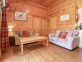 A living room with two sofas a wooden coffee table wooden walls and doors and red plaid cushions at Chalet Lodge Bunks L1 in Combe Martin