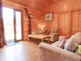 A living room with a wooden coffee table two beige sofas and curtains by a glass door at Chalet Lodge Bunks L1 in Combe Martin