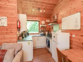 A kitchen area with a refrigerator, oven, sink, stove, and wooden walls at Chalet Lodge Bunks L1 in Combe Martin