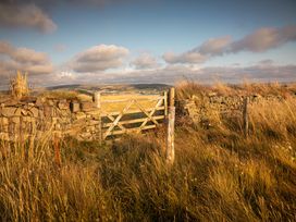 A gate next to a stone wall in a grassy landscape at 1 Manleigh Park Combe Martin