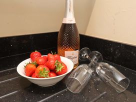 A bowl of strawberries and a bottle of sparkling wine in the kitchen at Hazelgarth House Hunmanby