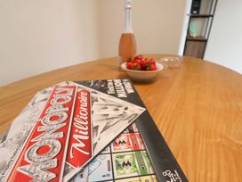 A dining table with Monopoly game, strawberries in a bowl, and a bottle at Hazelgarth House in Hunmanby