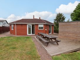 A house with a decking area and outdoor table at Hazelgarth House in Hunmanby