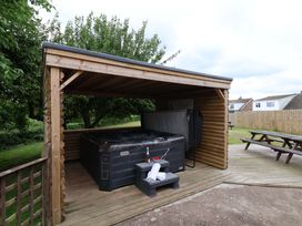 A hot tub in a wooden shelter with seating at Hazelgarth House in Hunmanby