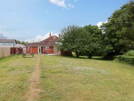 A garden with grass, trees and a house at Hazelgarth House in Hunmanby