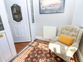A hallway with a chair, radiator, and a door at Fern Lee in Carlisle