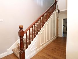 A staircase with a wooden handrail in a hallway at Fern Lee in Carlisle