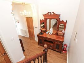 A hallway with a chandelier and wooden furniture at Fern Lee in Carlisle