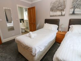 A bedroom with twin beds and a bathroom in view at Fern Lee in Carlisle