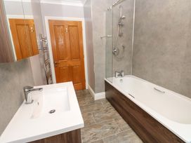A bathroom with a bath tub, sink and mirror at Fern Lee in Carlisle