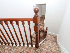 A staircase with a wooden banister and patterned carpet at Fern Lee in Carlisle