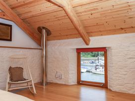 A bedroom with a rocking chair and a window overlooking the water at Dolphin Cottage Brixham