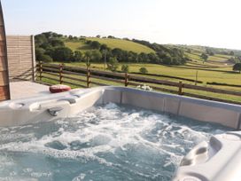 A hot tub on a deck with a view of fields and hills at Ceunant in Llanfihangel-y-Creuddyn near Aberystwyth