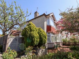 A residential house with bushes trees and a metal bench in a garden at Haffannedd in Rhos-On-Sea