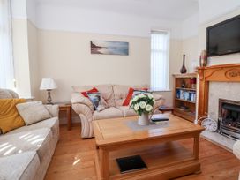 A living room with sofas a wooden coffee table flowers on the table a fireplace and a bookshelf at Haffannedd in Rhos-On-Sea