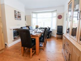 A dining room with a wooden table set for six people and black chairs at Haffannedd in Rhos-On-Sea
