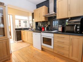 A kitchen with wooden cabinets a dishwasher an oven a microwave and a black countertop at Haffannedd in Rhos-On-Sea