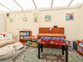 A room with a foosball table a piano a red table with chairs a bookshelf a beige sofa and bean bags at Haffannedd in Rhos-On-Sea